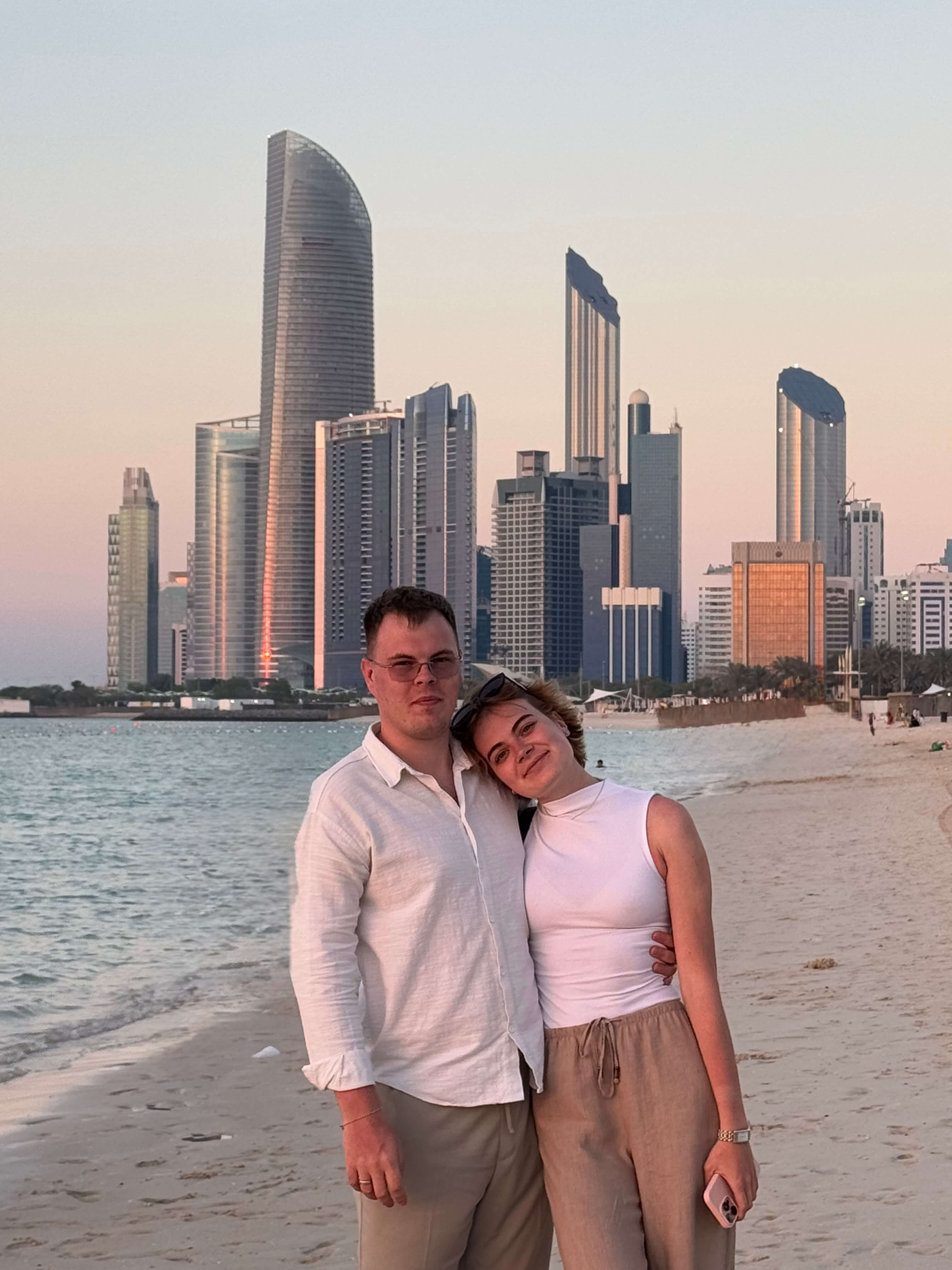 Mikhail and Anna on the beach with a city skyline in the background